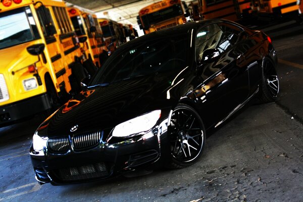 BMW noir sur fond d autobus scolaires