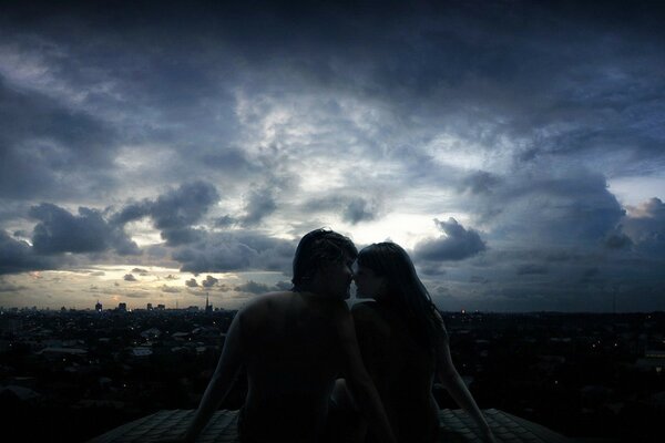 Love couple on the roof in the city in the evening