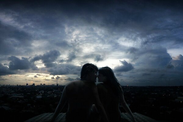 Любовная пара на крыше в городе вечером