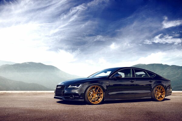 Audi A7 bleu sur fond de montagnes et ciel vue latérale