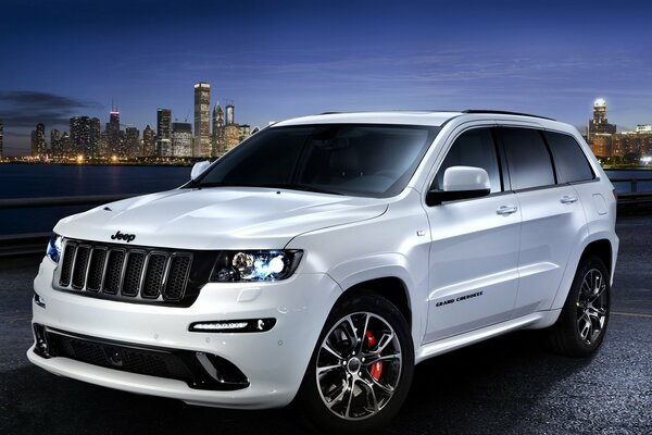 Автомобиль jeep grand cherokee на фоне ночного города