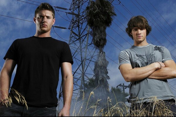 Young men against the background of high-voltage lines, blue sky and smoking pipe