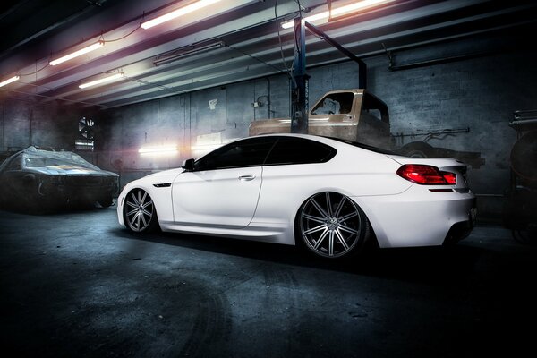 White BMW m6 in the garage against the background of old cars