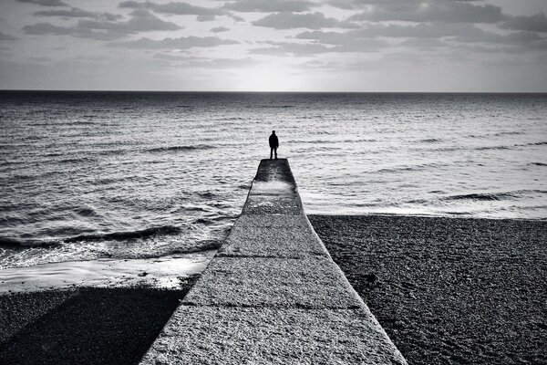 Black-and-white background, a man on a pier going into the horizon