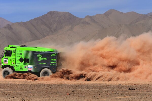 Camión verde a alta velocidad conduciendo por el desierto