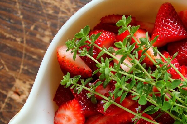 Erdbeeren in einer weißen Schüssel mit Graszweigen