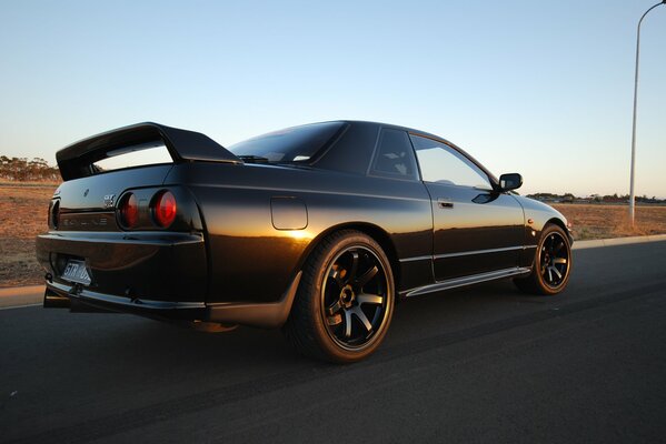 Black nissan on the road in the field