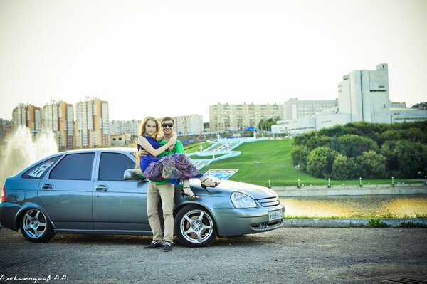 Un chico sostiene a una chica en el fondo de un Lada