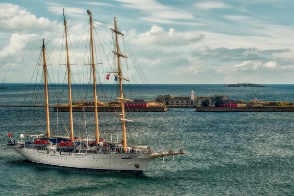 Navire avec des voiles baissées près du phare