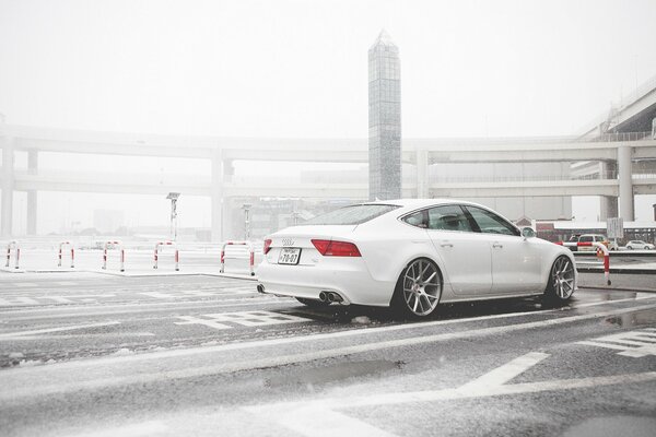 Белый audi a7 едет по снегу