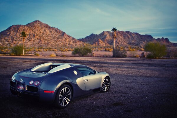 Bugatti in the desert against the background of mountains in the evening light