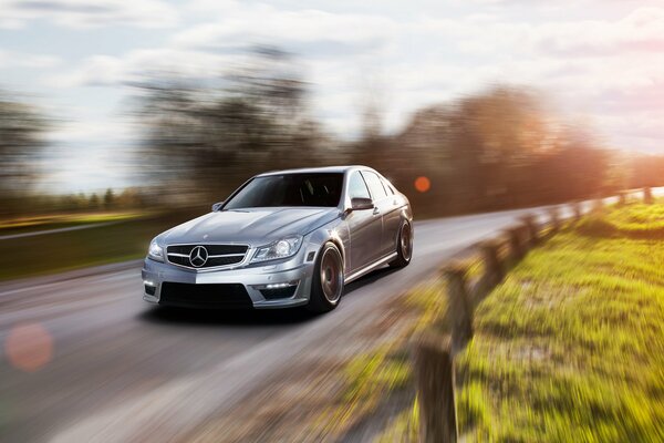 Srebrny Mercedes C63 amg w ruchu na drodze