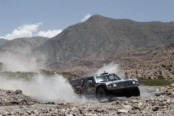 Un Jeep todoterreno en las montañas conduce a través de un arroyo