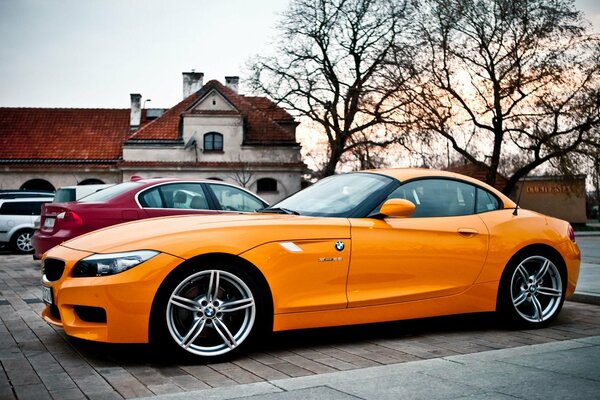 Cerchi fantastici di una BMW arancione sullo sfondo di una città autunnale