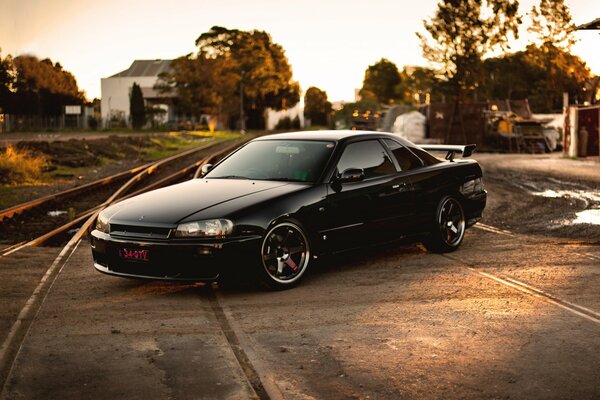 Black nissan on rails against autumn trees