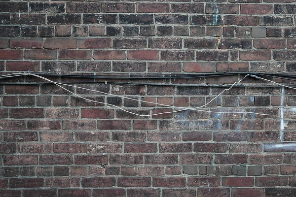 The cable is hanging on a brick wall