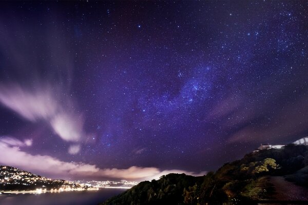 The starry sky above the mountains in the distance you can see the city