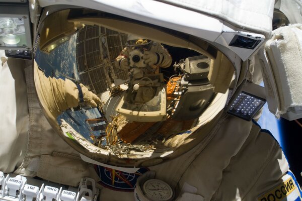Dos astronautas son fotografiados en el espacio a través de un reflejo en un casco de traje espacial