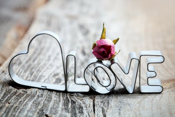 Letras con una rosa y un corazón en la cubierta de madera