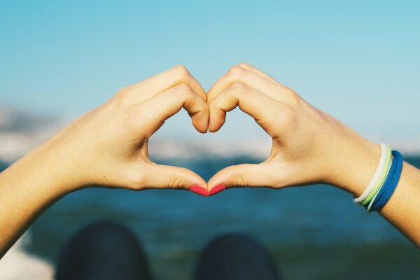 Cuore dalle mani sullo sfondo del mare