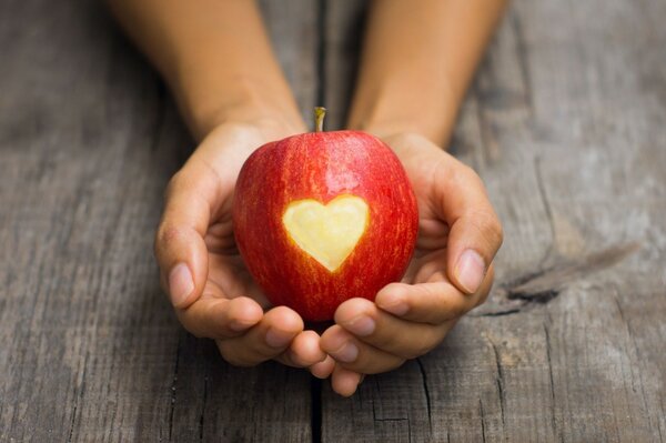 Roter Apfel mit Herz in den Handflächen