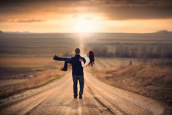Любовная пара гуляющая по дороге любуясь закатом