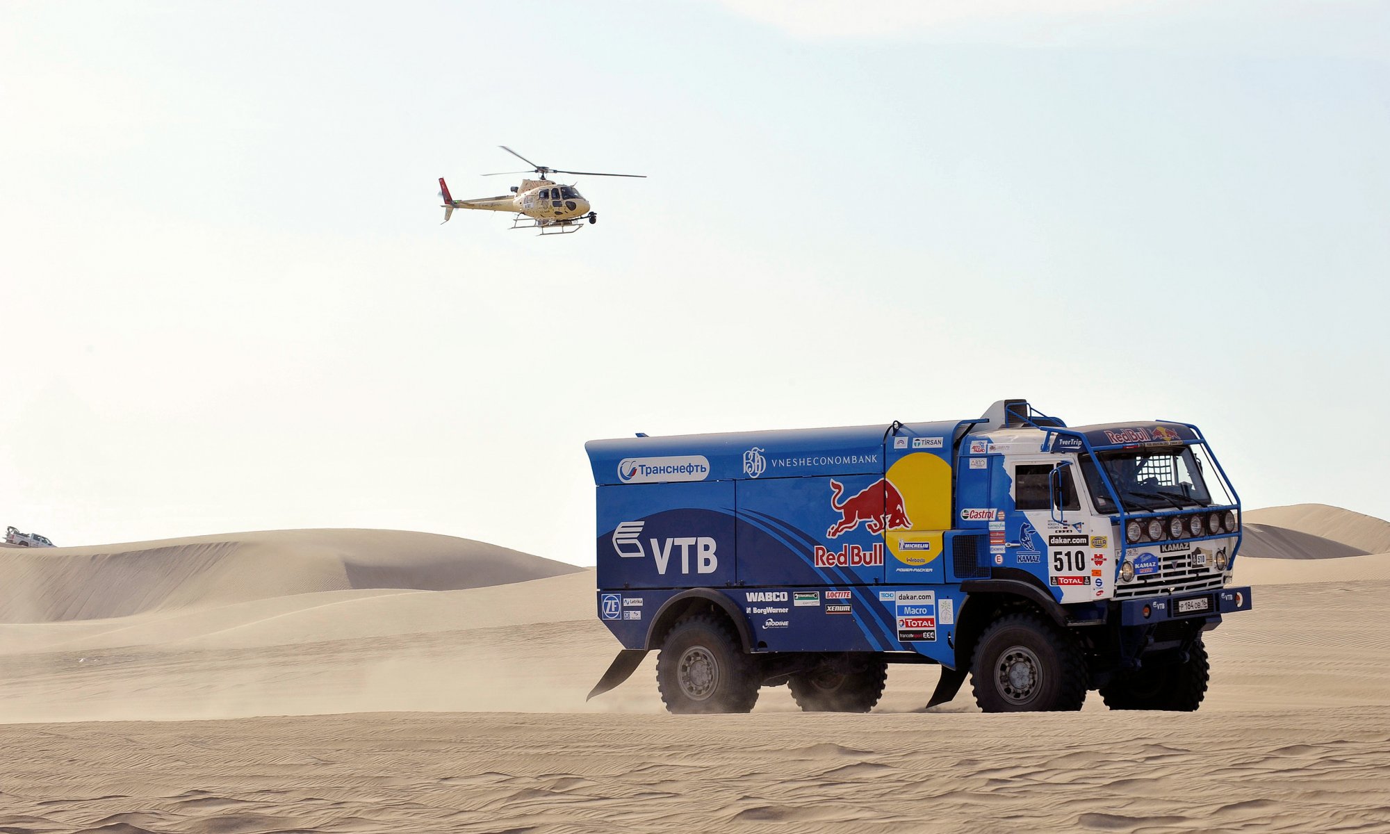 kamaz ciężarówka rajd dakar niebieski czerwony byk widok z boku auto samochód helikopter pustynia wyścig sport upał dzień rajd