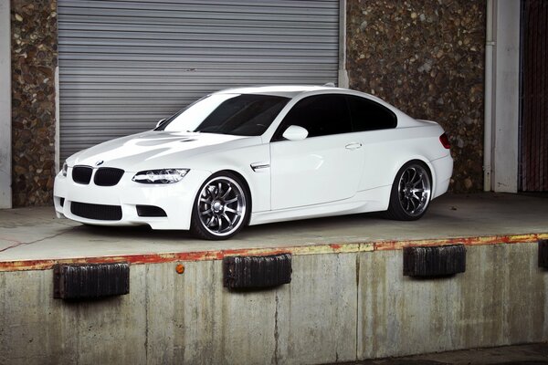 Une BMW blanche garée près du garage