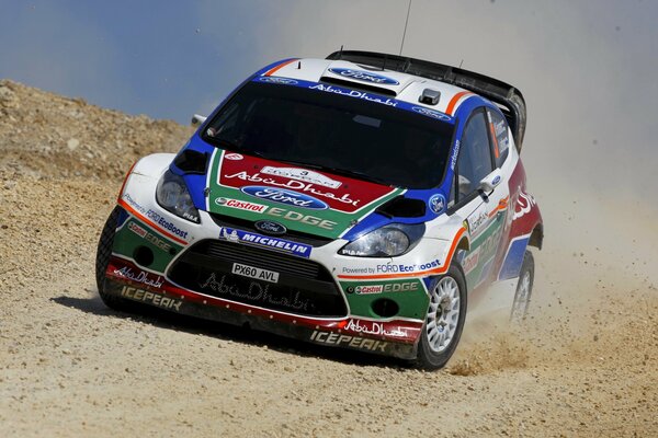 A racing car rides on a sandy road