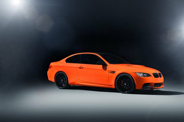 Marque de voiture orange BMW sur fond sombre à la lumière des projecteurs