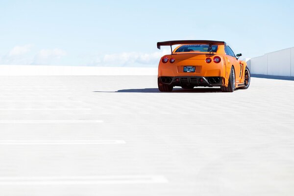 An orange Nissan is parked in the parking lot