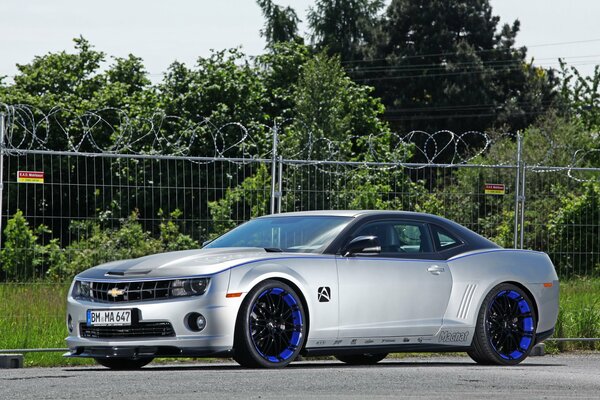 Car wallpaper with a tuned Chevrolet Camaro near a fence with barbed wire