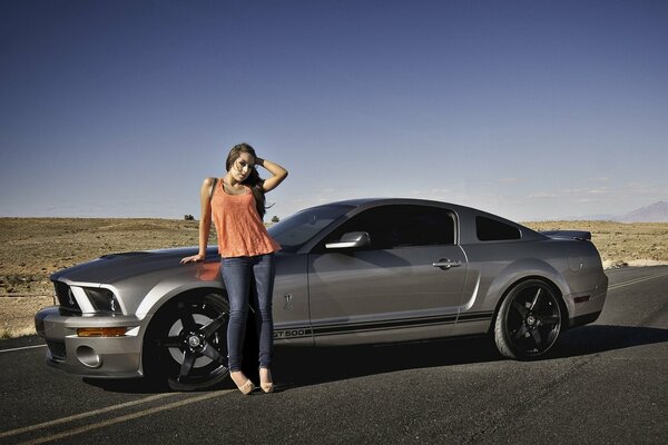 Beautiful girl next to a mustang GT 500 in the desert