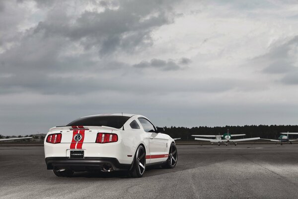 Ford Mustang blanco en el carril del avión