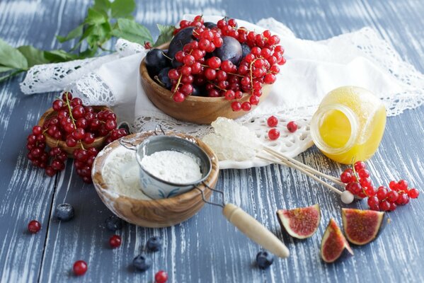 On the table are red currants, honey, figs, flour