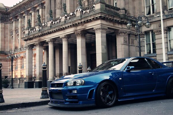 Blue nissan skyline on the background of an old building