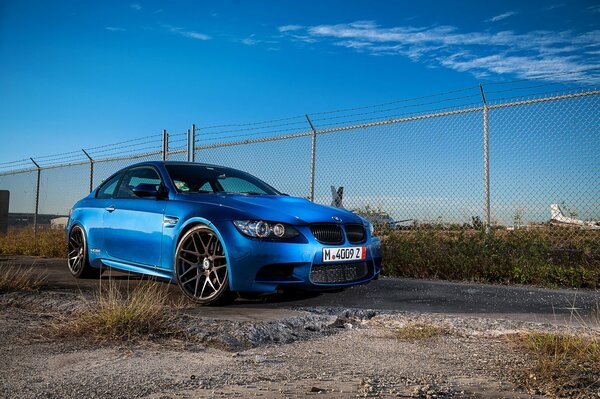Błękitne jak niebo piękne BMW M3 czaiło się przy ogrodzeniu