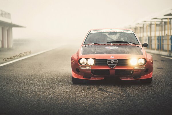 Red alfa romeo with headlights on