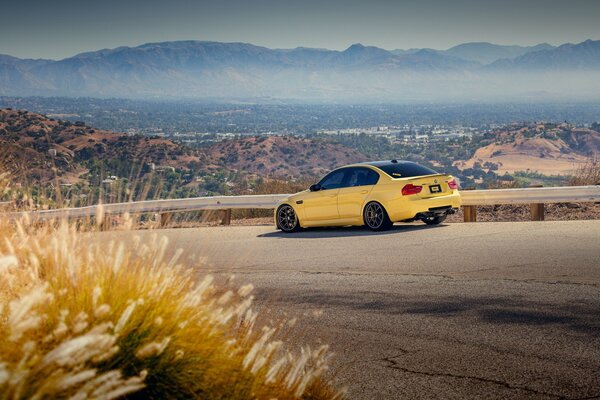 Yellow BMW on the highway, and in the distance mountains, town