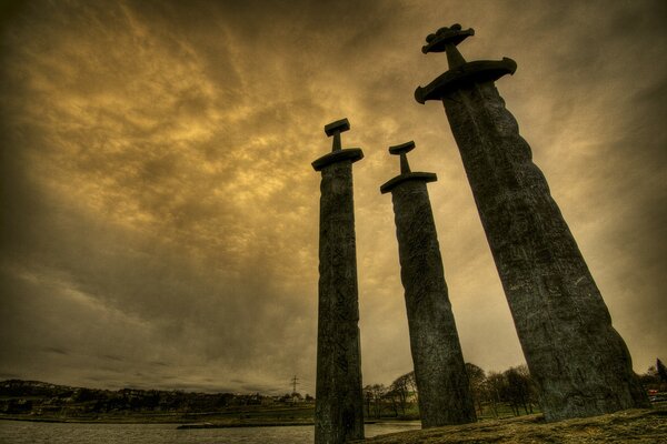 Three stone swords against the burning sky