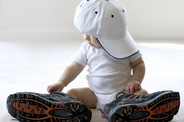 A child in a cap and big sneakers