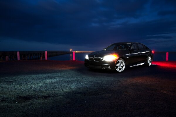 Bmw F10 noire sur la jetée de nuit