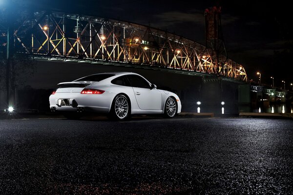 Weißer Porsche auf dem Hintergrund der Brücke, in der Nacht