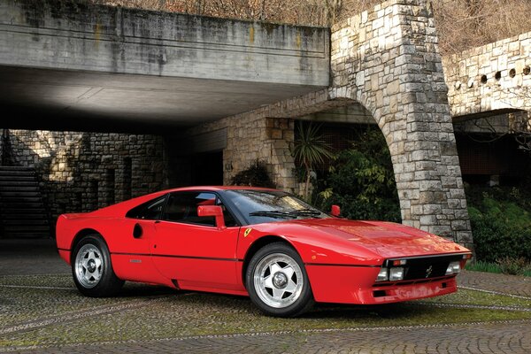 Red Ferrari on the road under the bridge