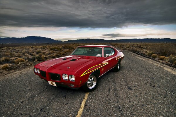 A red Pontiac car turned around on the road