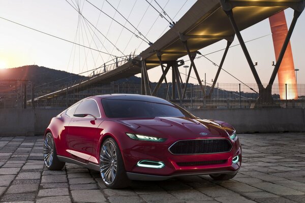 Ford rojo al atardecer bajo el puente