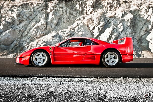 Auto sportiva rossa del marchio Ferrari su uno sfondo di rocce