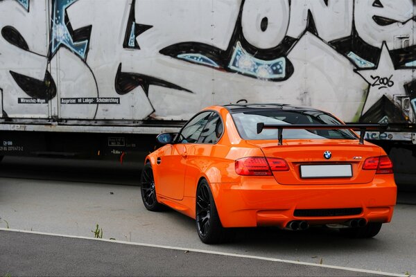 Orange bmw Coupé auf Wand Hintergrund mit Graffiti