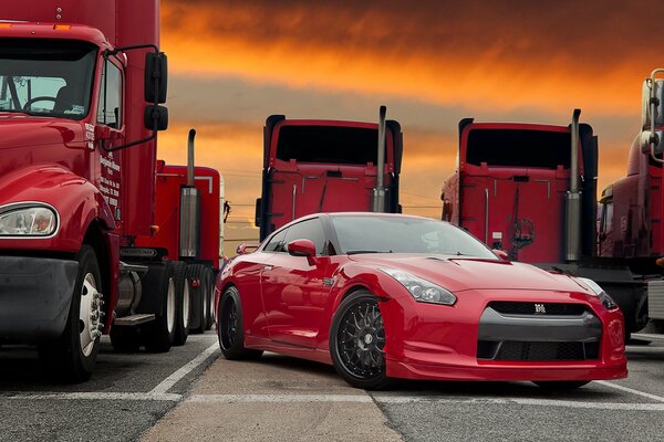 Red sports car on the background of red trucks