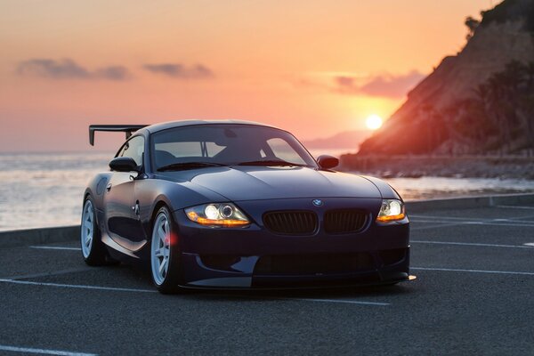 Voiture bmw z4 au coucher du soleil sur la côte de la mer